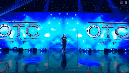 A Man Is Standing In Front Of A Stage That Says Otc On It GIF