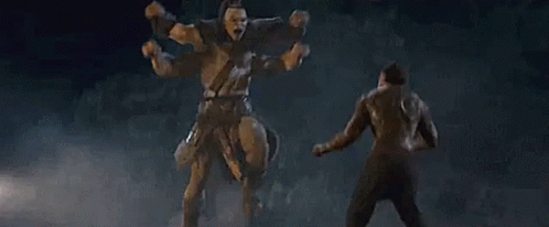 A Man Is Standing In Front Of A Statue Of A Giant Warrior . GIF