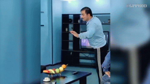 A Man Is Standing In Front Of A Table With A Bowl Of Fruit On It .. GIF