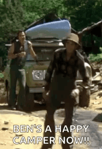 A Man Is Standing In Front Of A Truck With A Camper On The Back Of It . GIF