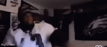 A Man Is Standing In Front Of A Wall With A Picture Of An Eagles Jersey On It . GIF