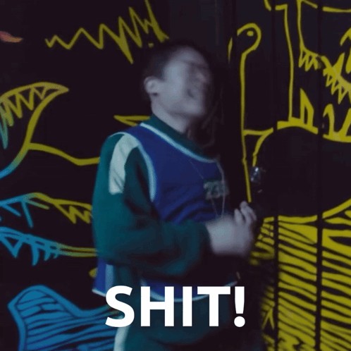 A Man Is Standing In Front Of A Wall With Drawings On It And The Word Shit Written On It GIF
