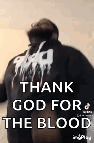 A Man Is Standing In Front Of A Wall With The Words `` Thank God For The Blood '' Written On His Back . GIF