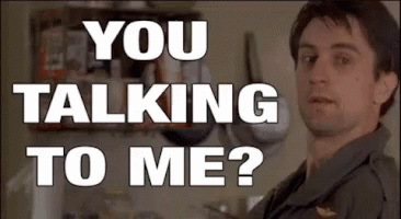 A Man Is Standing In Front Of A Wall With The Words `` You Talking To Me ? '' Written On It . GIF
