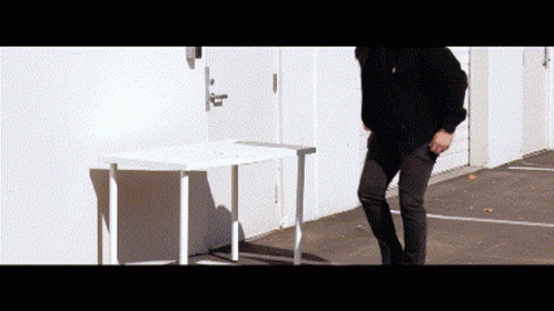 A Man Is Standing In Front Of A White Table . GIF