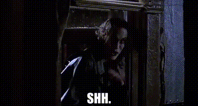 A Man Is Standing In Front Of A Window And Holding A Gun . GIF