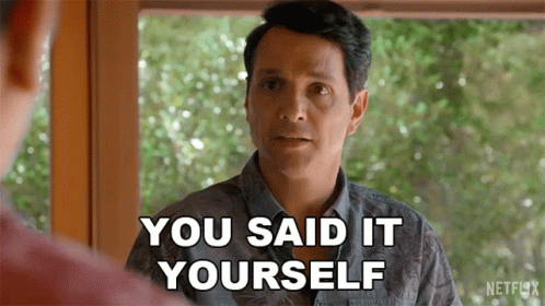 A Man Is Standing In Front Of A Window And Talking To Another Man . GIF