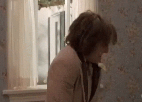 A Man Is Standing In Front Of A Window In A Room With A Floral Wallpaper . GIF