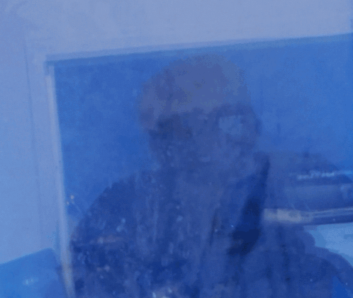 A Man Is Standing In Front Of A Window That Says Powered On It GIF