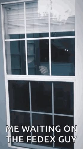 A Man Is Standing In Front Of A Window Waiting For A Fedex Guy . GIF