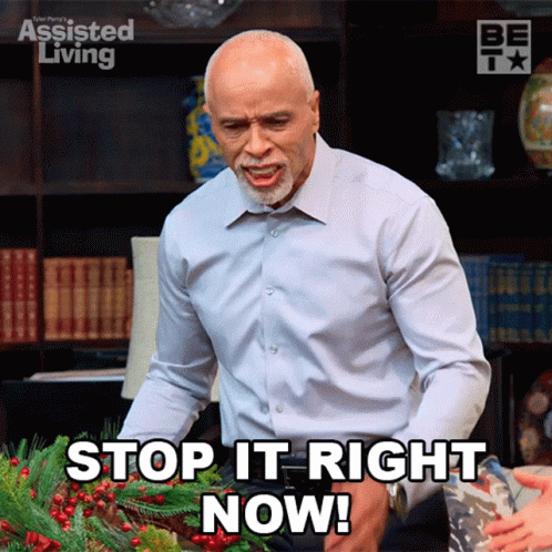 A Man Is Standing In Front Of A Wreath And Says Stop It Right Now GIF