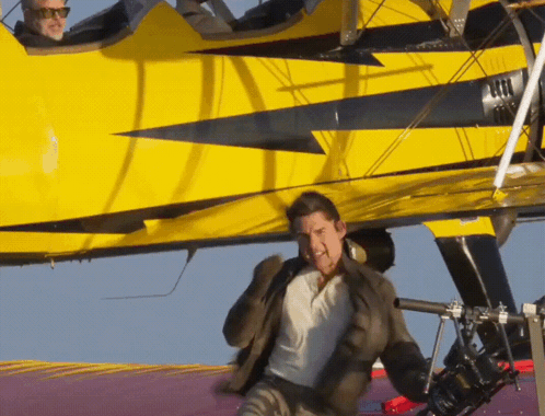 A Man Is Standing In Front Of A Yellow Plane GIF
