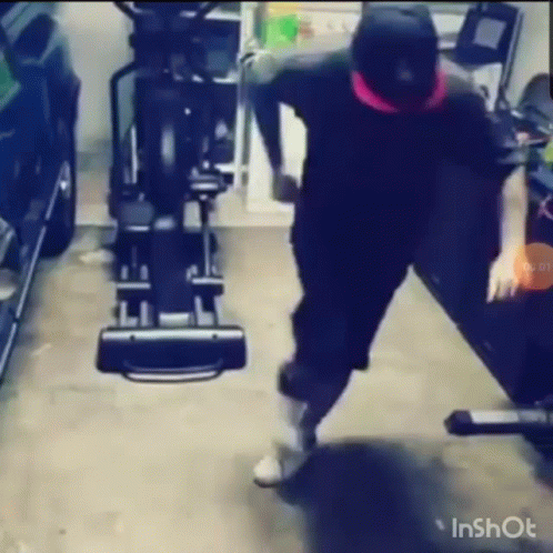 A Man Is Standing In Front Of An Elliptical Machine In A Garage . GIF