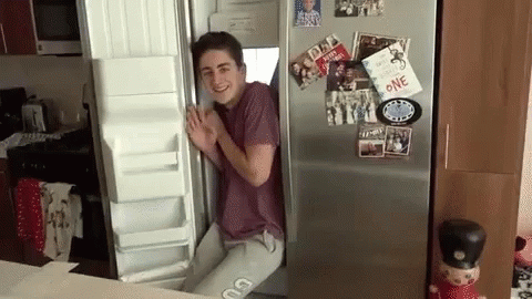 A Man Is Standing In Front Of An Open Refrigerator With A Card That Says One On It GIF