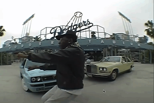 A Man Is Standing In Front Of Dodgers Stadium GIF