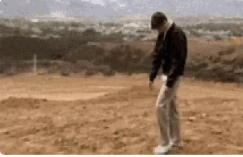 A Man Is Standing In The Middle Of A Dirt Field GIF