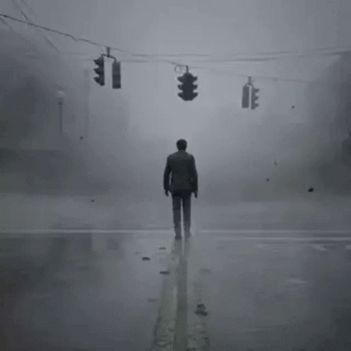 A Man Is Standing In The Middle Of A Foggy Street . GIF