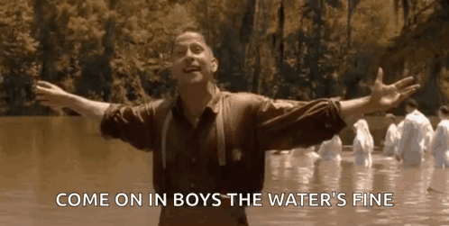 A Man Is Standing In The Water With His Arms Outstretched And A Group Of People Are Standing In The Water . GIF