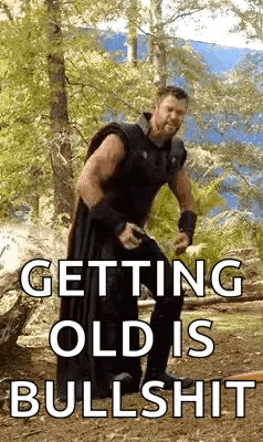 A Man Is Standing In The Woods With The Words `` Getting Old Is Bullshit '' . GIF