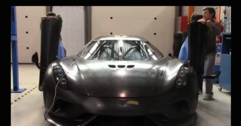 A Man Is Standing Next To A Black Sports Car With Its Doors Open GIF