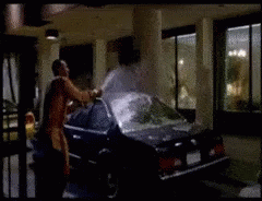 A Man Is Standing Next To A Car In A Parking Garage GIF