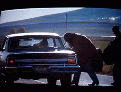 A Man Is Standing Next To A Car With A License Plate That Says ' Lc ' On It GIF