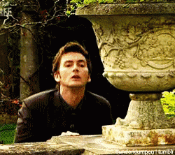 A Man Is Standing Next To A Large Stone Vase With The Word R.e.f. On It GIF