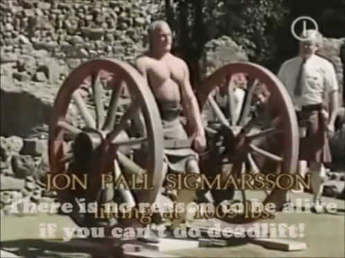 A Man Is Standing Next To A Pair Of Wagon Wheels With The Words Jon Pall Sigmarsson Written On The Bottom GIF