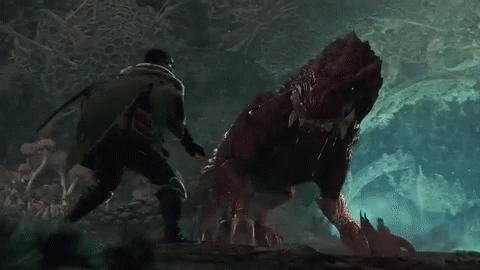 A Man Is Standing Next To A Red Monster In A Cave . GIF