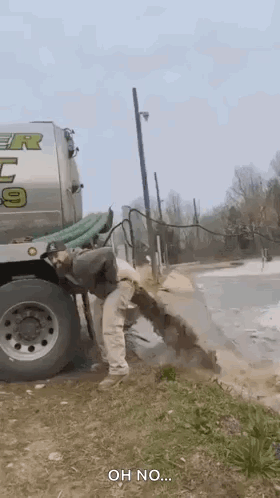 A Man Is Standing Next To A Septic Tank Truck . GIF