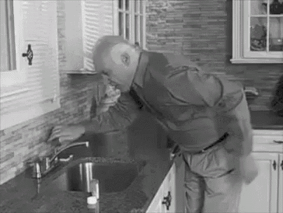 A Man Is Standing Next To A Sink In A Kitchen . GIF