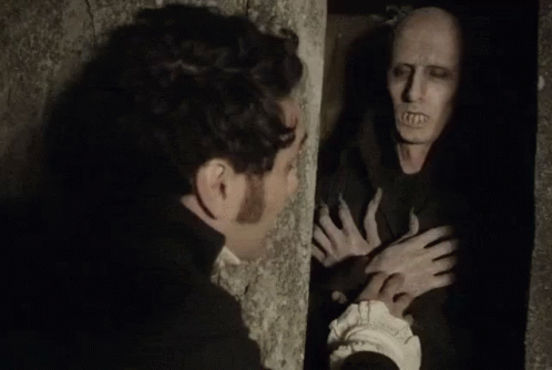 A Man Is Standing Next To A Wall Looking At A Monster . GIF