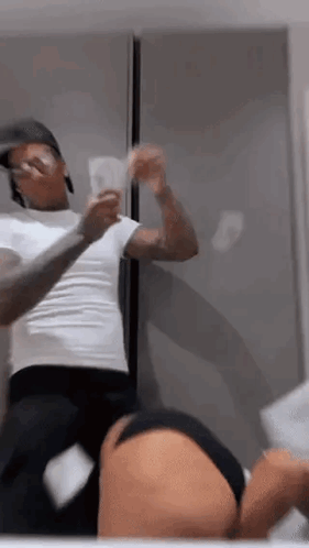 A Man Is Standing Next To A Woman In A Bathroom Holding A Bunch Of Money In Front Of A Mirror . GIF