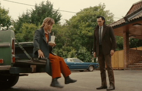 A Man Is Standing Next To A Woman Sitting In The Back Of A Truck . GIF