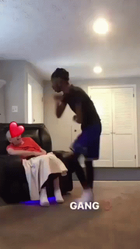 A Man Is Standing Next To A Woman Sitting On A Couch And The Word Gang Is On The Bottom GIF