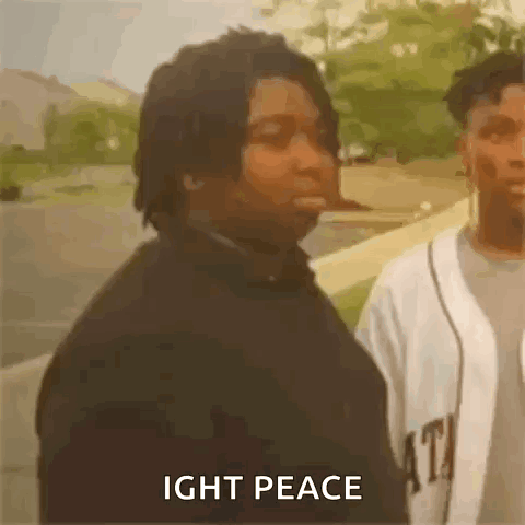 A Man Is Standing Next To Another Man With The Words `` Ight Peace '' Written On The Screen . GIF
