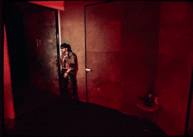 A Man Is Standing On A Balcony Looking Out At The City At Night GIF