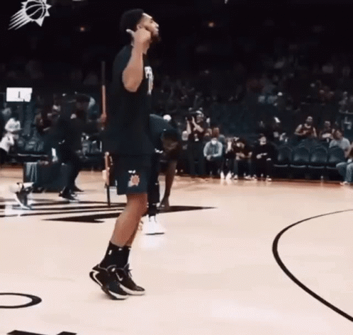 A Man Is Standing On A Basketball Court And Giving A Thumbs Up . GIF