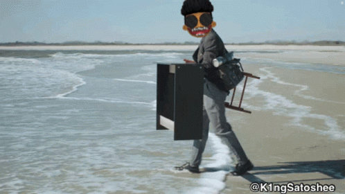 A Man Is Standing On A Beach With A Ladder On His Back And The Hashtag @Kingsatoshee On The Bottom GIF