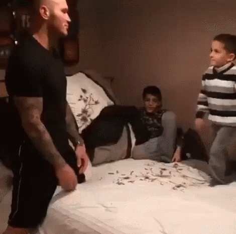 A Man Is Standing On A Bed Next To Two Boys . GIF
