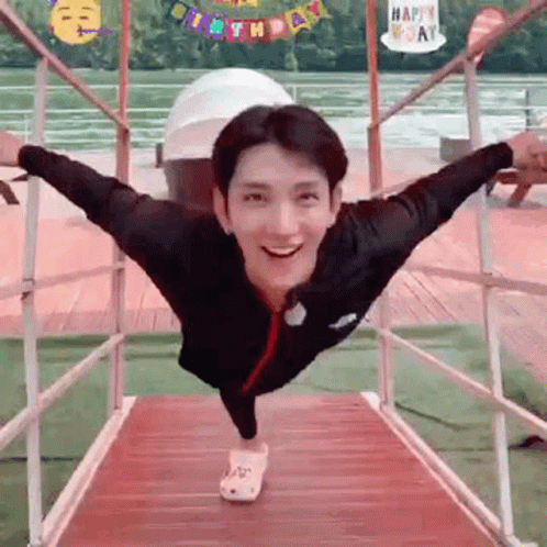 A Man Is Standing On A Bridge With His Arms Outstretched . GIF