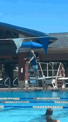 a man is standing on a diving board in a swimming pool
