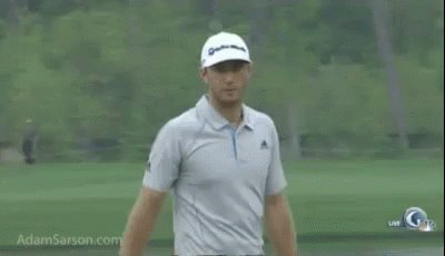 A Man Is Standing On A Golf Course Wearing A Hat And A Polo Shirt . GIF