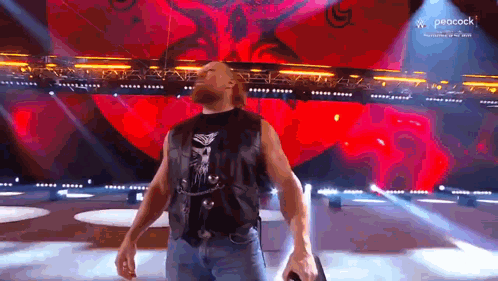A Man Is Standing On A Stage Holding A Microphone . GIF