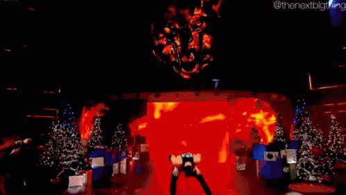 A Man Is Standing On A Stage In Front Of Christmas Trees . GIF