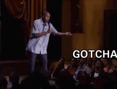 A Man Is Standing On A Stage With A Microphone In Front Of A Crowd Of People And Says Gotcha Bitch . GIF