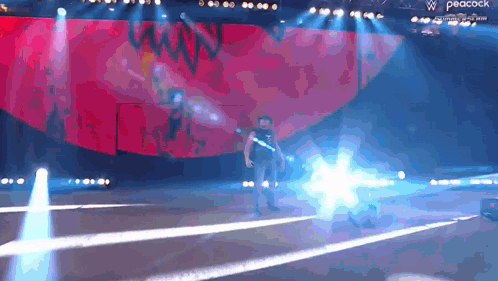 A Man Is Standing On A Stage With A Peacock Logo In The Background GIF