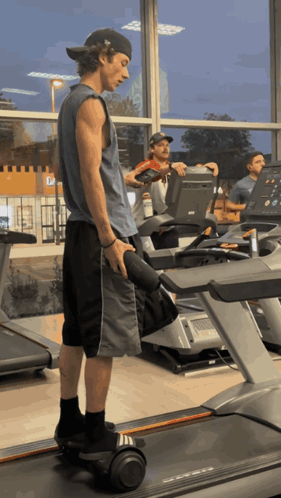 A Man Is Standing On A Treadmill Holding A Dumbbell In A Gym GIF