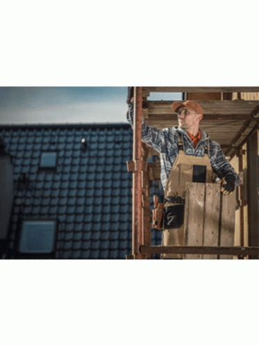 A Man Is Standing On A Wooden Scaffolding Looking Up At The Sky GIF