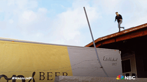A Man Is Standing On The Roof Of A Building Next To A Beef Truck GIF